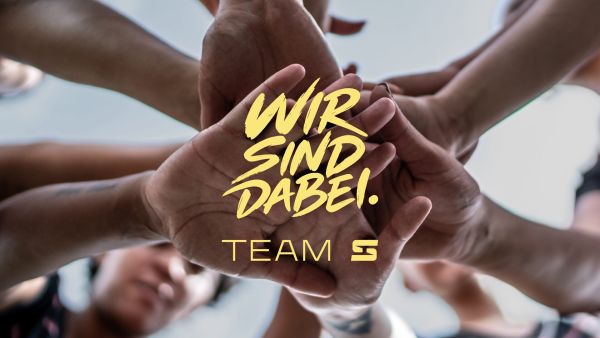 Aufeinandergelegte Hände mit dem Schriftzug Wir sind dabei. Team S